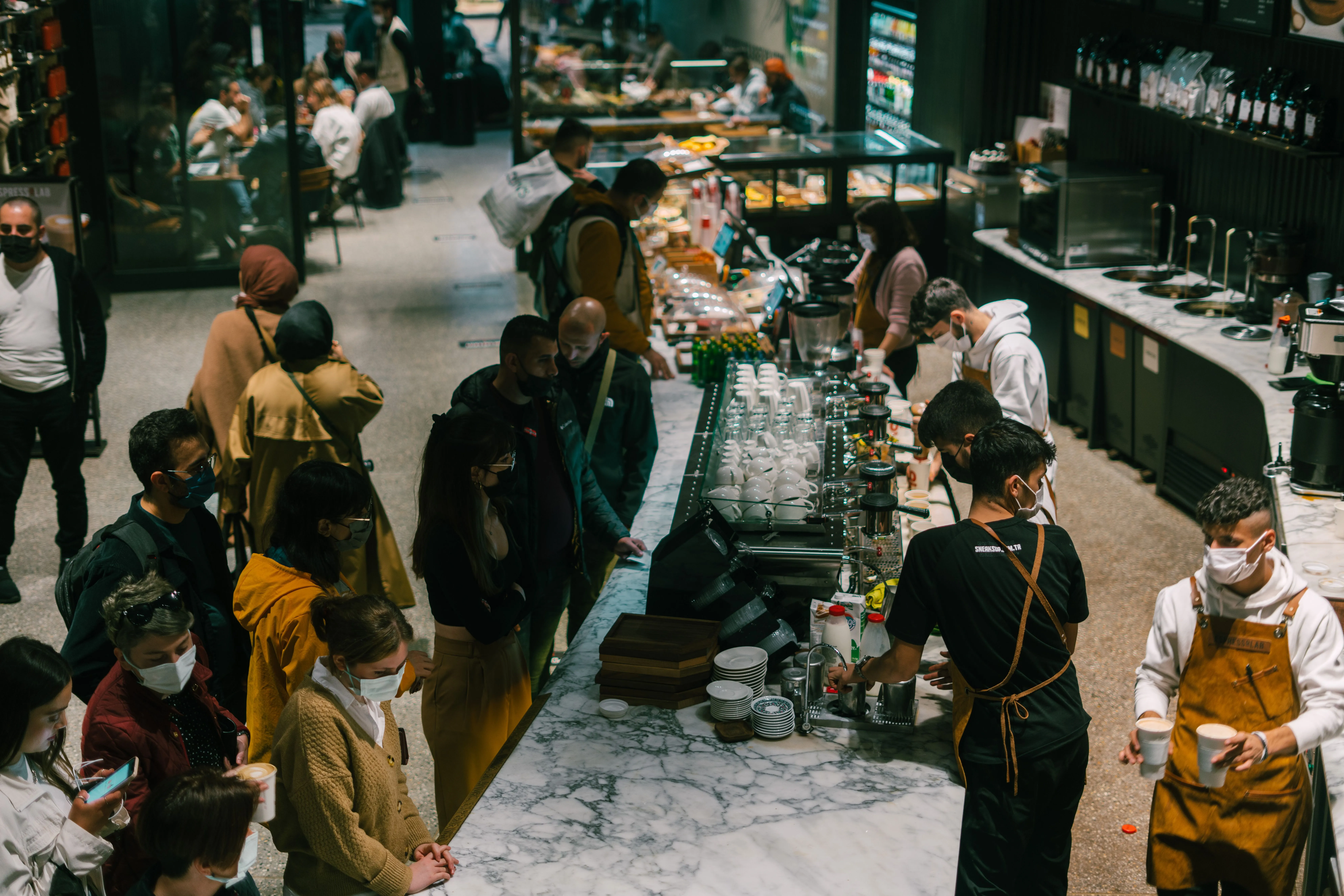 A bustling cafe with customers waiting in line, highlighting the need to reduce wait times with QR ordering.