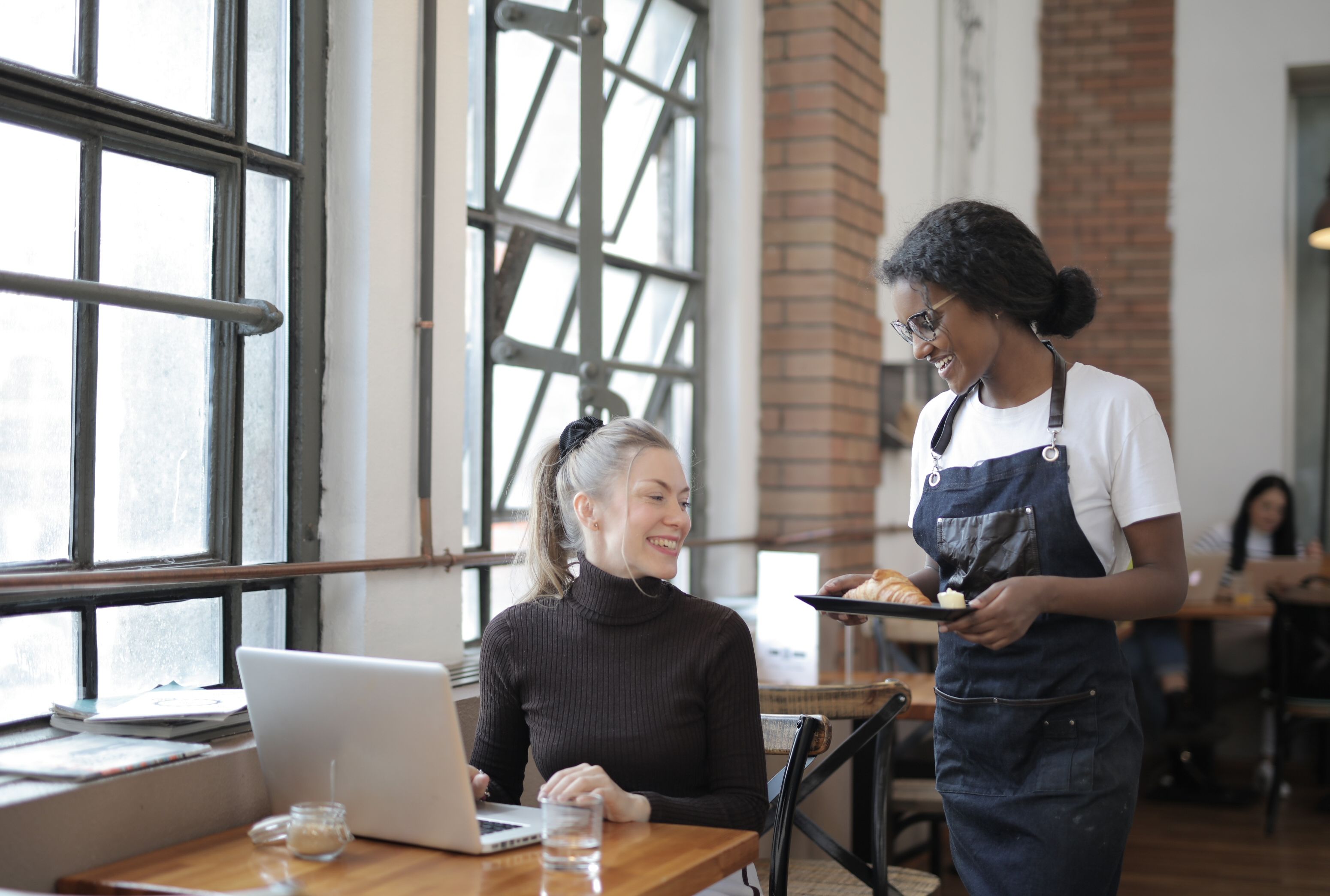 Cafe waiter serving a customer, backed by real-time POS inventory synchronization to prevent out-of-stock orders.